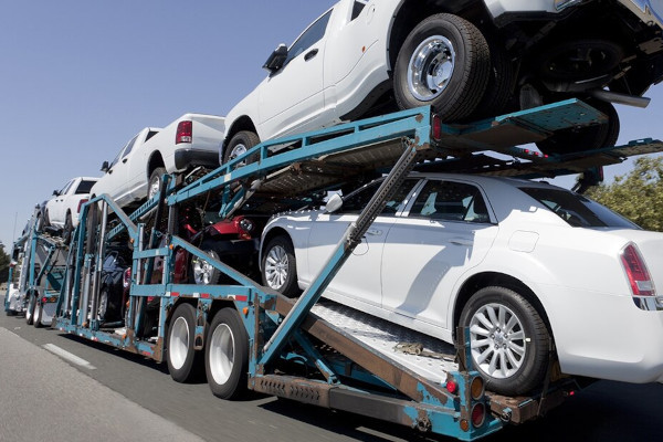 Rear view of trailer of new cars and trucks speeding to market.